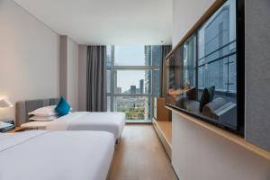 a hotel room with a bed and a flat screen tv at Pagoda Hotel Shenzhen in Shenzhen