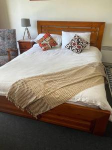 een houten bed met kussens erop bij Violet Cottage in the City in Hobart