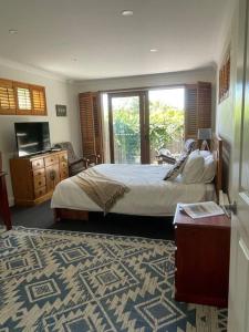 Schlafzimmer mit einem Bett, einem TV und einem Fenster in der Unterkunft Violet Cottage in the City in Hobart