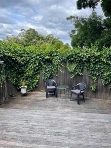 twee stoelen en een tafel voor een hek bij Violet Cottage in the City in Hobart