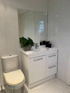 een witte badkamer met een toilet en een wastafel bij Violet Cottage in the City in Hobart