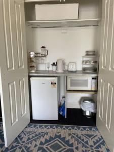 een kleine keuken met een witte koelkast en een magnetron bij Violet Cottage in the City in Hobart