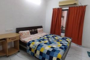 a bedroom with a bed and a desk and curtains at AG House Daman holiday Home apartment in Daman