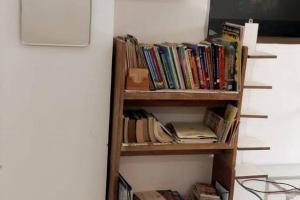 una mensola piena di libri accanto a un muro di AG House Daman holiday Home apartment a Daman