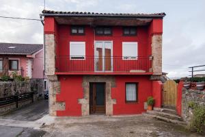 uma casa vermelha com uma varanda numa rua em Precioso piso estilo rústico a 10 min de Santander em Camargo