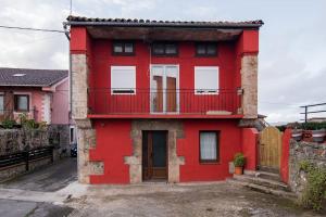 a red house with a balcony on a street at Precioso piso estilo rústico a 10 min de Santander in Camargo