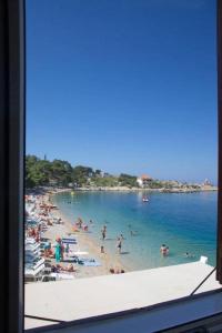 uma praia com um monte de pessoas na água em Beach rooms Riviera - Žuta Kuća em Makarska