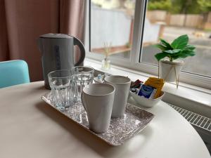 a tray with cups and glasses on a table with a window at The Lily Pad in Corfe Mullen