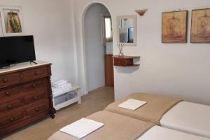 Schlafzimmer mit einem Bett und einer Kommode mit einem TV in der Unterkunft Aspartia in Naxos Chora