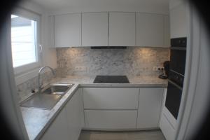 uma cozinha com armários brancos, um lavatório e uma janela em "Zee en rust" em De Haan