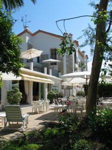 a patio with tables and chairs and a building at Hotel Pierre Loti in Juan-les-Pins