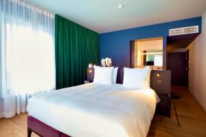a bedroom with a large white bed with green curtains at U Eat & Sleep Antwerp in Antwerp