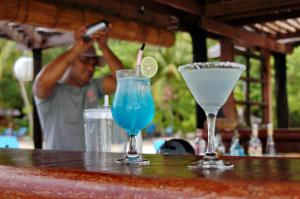 Zwei Cocktails auf dem Tisch, mit einem Mann, der ein Foto macht. in der Unterkunft Raja Ampat Dive Lodge in Pulau Mansuar