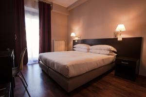 1 dormitorio con 1 cama grande con sábanas y almohadas blancas en Hotel di Porta Romana, en Milán