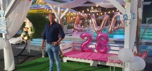 a man standing in front of a marquee with a pink number at La Păstrăvărie in Mehadia +27 photos