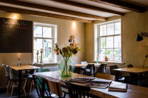 un restaurant avec des tables, des chaises et un vase de fleurs dans l'établissement Bij Hen op Ameland, à Hollum
