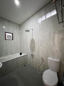 y baño con aseo, lavabo y ducha. en Wisma Selma Garuda en Kejayan