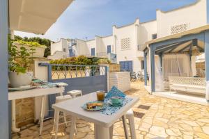 un patio con tavolo e sedie bianchi e un balcone. di Appartamento Playa Lapillo a Nardò