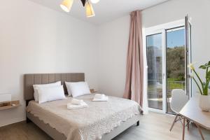 a white bedroom with a bed and a large window at Villa Resperi in Gonia