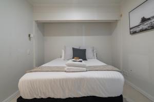 a white bedroom with a bed with towels on it at Luxury Apartment - Parking - Hot Tub - Stunning Views in Auckland