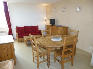 sala de estar con mesa, sillas y sofá rojo en Les coquelicots, en Lhommaizé