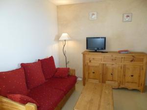 sala de estar con sofá rojo y TV en Les coquelicots, en Lhommaizé