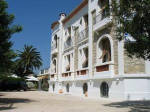 a large white building with a palm tree in front of it at Hotel Pierre Loti in Juan-les-Pins