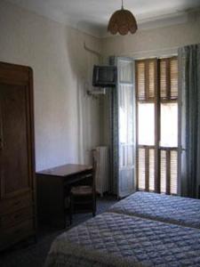 a bedroom with two beds and a desk and a window at Hotel Pierre Loti in Juan-les-Pins