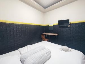 - une chambre avec un lit blanc et un bureau dans l'établissement Superstar Residence Tomohon Redpartner, à Tomohon