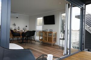 a living room with a table and a tv on the wall at Hausboot Kajüte am Nixensteg Am Wangermeer mit Hund in Wangerland