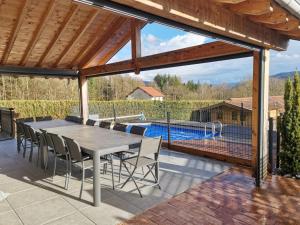 um pátio com uma mesa e cadeiras e uma piscina em L'écrin de Xattys - Gîte de standing-SPA-terrain de pétanque-Piscine-Switch-Baby-foot au coeur du Massif Vosgien em Cleurie