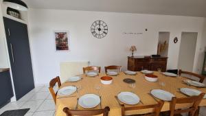 tavolo da pranzo con piatti, sedie e orologio di L'Ange gîte de groupe proche du Puy du Fou a Sevremont