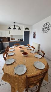 un lungo tavolo con piatti e sedie in cucina di L'Ange gîte de groupe proche du Puy du Fou a Sevremont