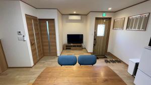 ein Wohnzimmer mit 2 blauen Stühlen und einem TV in der Unterkunft 富士山下Cottage-A in Narusawa