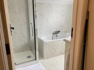 La salle de bains blanche est pourvue d'une douche et d'un lavabo. dans l'établissement Peaceful Home in Guildford Surrey UK -Free Parking, Garden, River & Waterfall, à Bramley