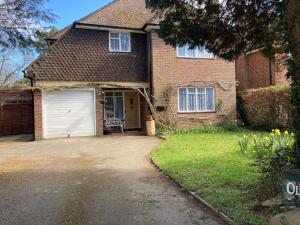 a brick house with a garage and a driveway at Peaceful Home in Guildford Surrey UK -Free Parking, Garden, River & Waterfall in Bramley