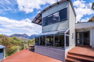 una casa con terraza con montañas al fondo en Haven on Bradley, en Coles Bay