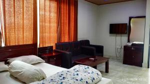 una habitación de hotel con 2 camas y una silla en HOTEL MOHSIN PLAZA en Sreemangal