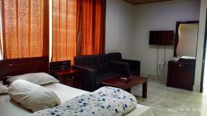 a hotel room with two beds and a chair at HOTEL MOHSIN PLAZA in Sreemangal