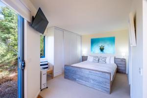 Un dormitorio con una cama y un televisor en una pared. en Haven on Bradley, en Coles Bay