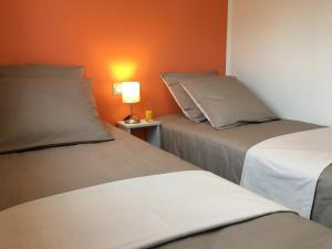Duas camas num quarto com uma parede laranja em Mandarine la vallee des noyers em Lhommaizé