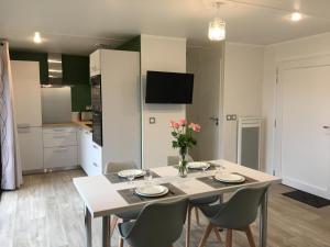 a dining room with a table and chairs and a kitchen at Granny la vallée des noyers in Lhommaizé