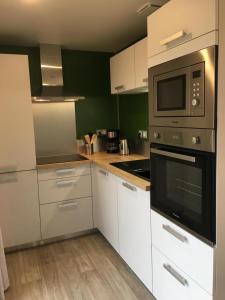 a kitchen with white cabinets and a microwave at Granny la vallée des noyers in Lhommaizé +4 photos