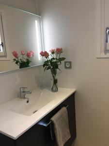 a bathroom with a sink with a vase of pink flowers at Granny la vallée des noyers in Lhommaizé