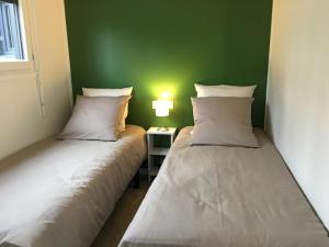 two beds in a room with a green wall at Granny la vallée des noyers in Lhommaizé