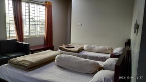 Cette chambre comprend 3 lits, une chaise et une fenêtre. dans l'établissement HOTEL MOHSIN PLAZA, à Sreemangal