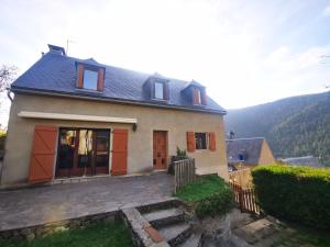 a house with orange doors and a mountain in the background at Maison Aulon (Saint Lary) in Aulon