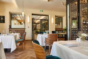 Olivier Leflaive Hôtel Restaurants في بوليغني-مونتراتشيت: مطعم بطاولات بيضاء وكراسي ونوافذ