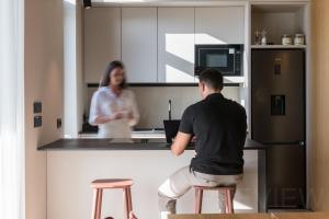 a man sitting on a stool in a kitchen with a woman at Vila Laguna Strunjan - Terme Krka in Strunjan