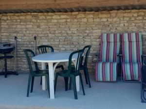 stół i krzesła siedzące obok ściany z cegły w obiekcie La bergerie 